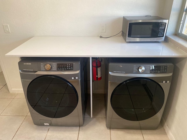 clothes washing area featuring light tile patterned floors, laundry area, and washing machine and dryer