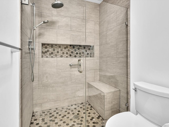 bathroom featuring a shower with door and toilet