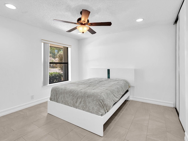 bedroom with ceiling fan and a textured ceiling