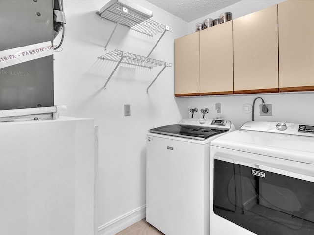 clothes washing area featuring cabinets, washer and dryer, and a textured ceiling