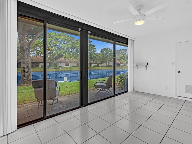 tiled spare room with ceiling fan, a water view, and a wealth of natural light