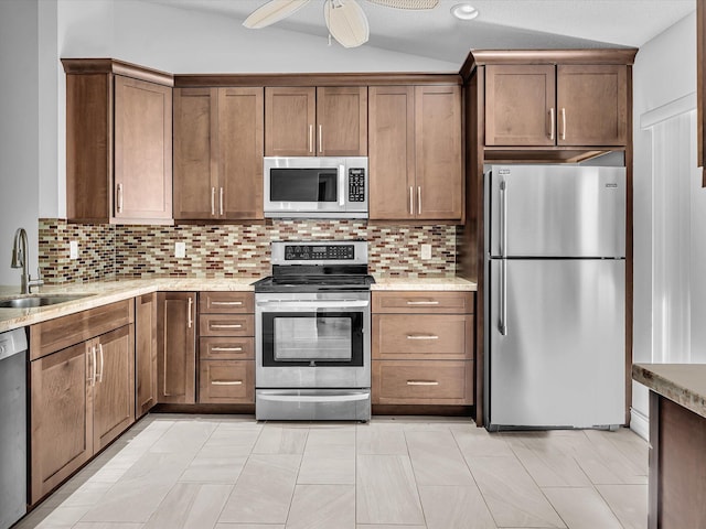 kitchen with appliances with stainless steel finishes, sink, lofted ceiling, and backsplash