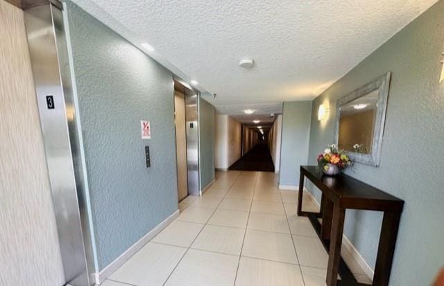 hallway with light tile patterned flooring and a textured ceiling