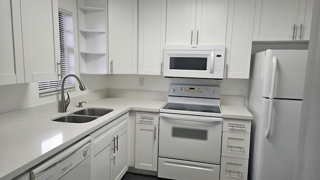 kitchen with white appliances, light stone countertops, white cabinetry, open shelves, and a sink