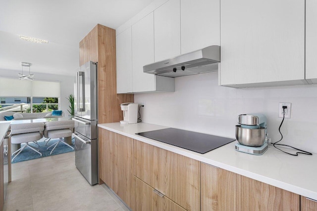 kitchen featuring black electric stovetop, stainless steel refrigerator, backsplash, and white cabinets