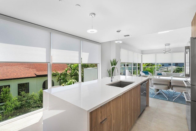 kitchen with stainless steel dishwasher, plenty of natural light, decorative light fixtures, and sink