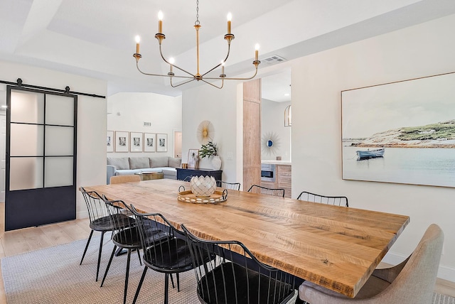 dining space with light hardwood / wood-style floors and a barn door