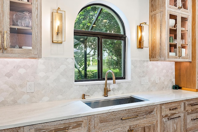 kitchen featuring sink, light stone counters, tasteful backsplash, and plenty of natural light