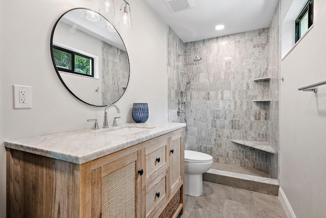 bathroom with vanity, toilet, tile patterned floors, and tiled shower