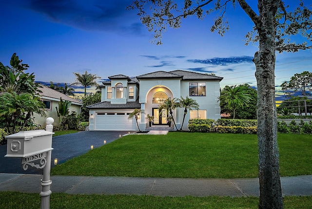 mediterranean / spanish home featuring a yard and a garage