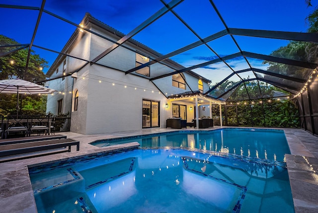 pool at dusk with a patio, an in ground hot tub, and glass enclosure