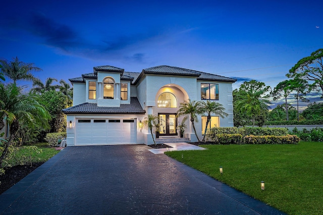 mediterranean / spanish-style house featuring a garage and a lawn