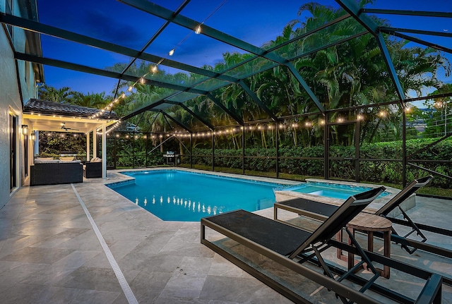 pool at dusk with a patio and glass enclosure