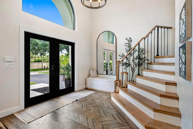 entrance foyer with french doors, dark parquet floors, and a high ceiling