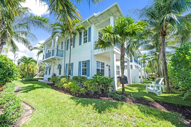 view of side of home with a balcony and a yard