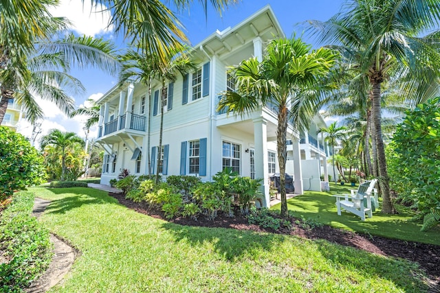 view of side of home with a yard, a balcony, and stucco siding