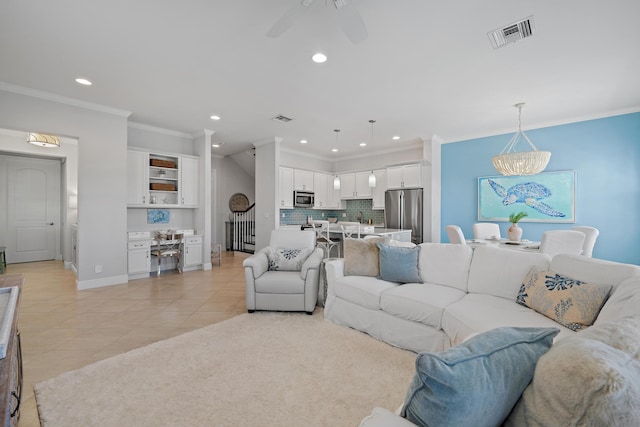 tiled living room with ceiling fan with notable chandelier and crown molding