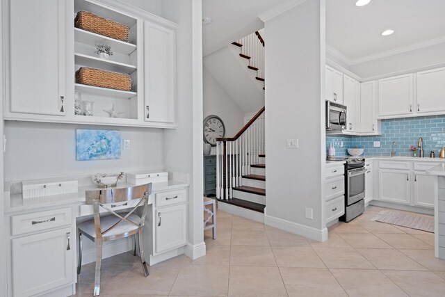 kitchen with crown molding, white cabinetry, light tile patterned floors, decorative backsplash, and appliances with stainless steel finishes