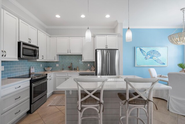 kitchen with appliances with stainless steel finishes, pendant lighting, crown molding, and sink