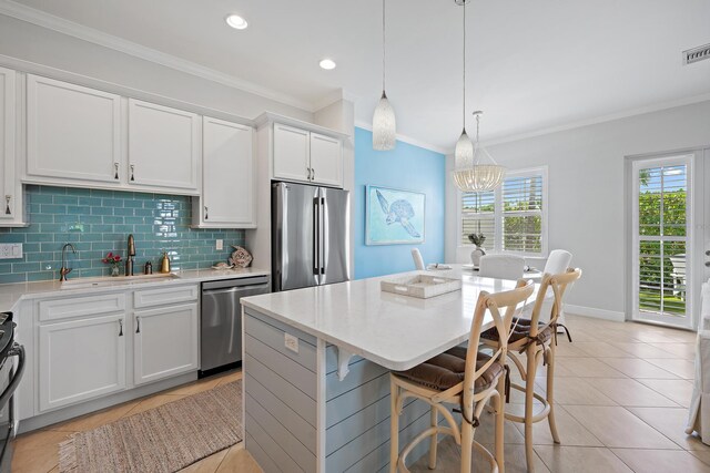 kitchen with a kitchen island, pendant lighting, appliances with stainless steel finishes, sink, and white cabinetry