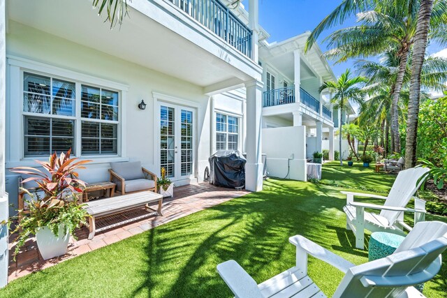 view of yard with a balcony, an outdoor living space, a patio area, and french doors