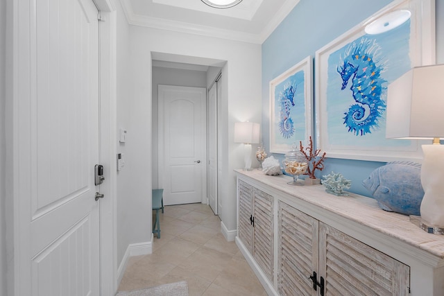 hall featuring light tile patterned floors, baseboards, and ornamental molding