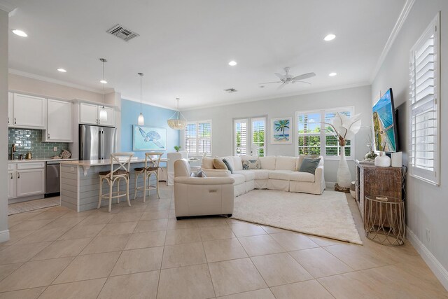 tiled living room with crown molding, ceiling fan, and sink