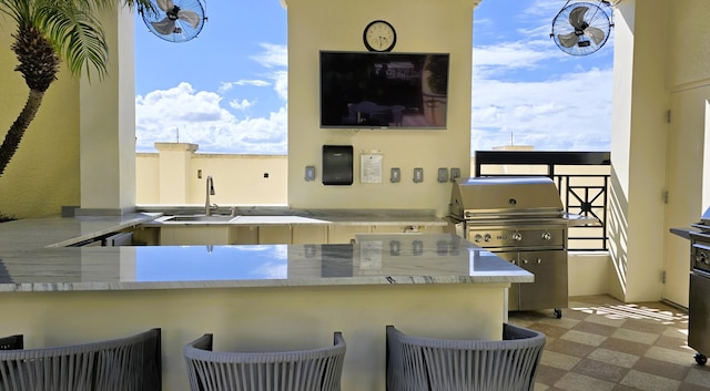 kitchen with a breakfast bar, light stone counters, kitchen peninsula, and sink