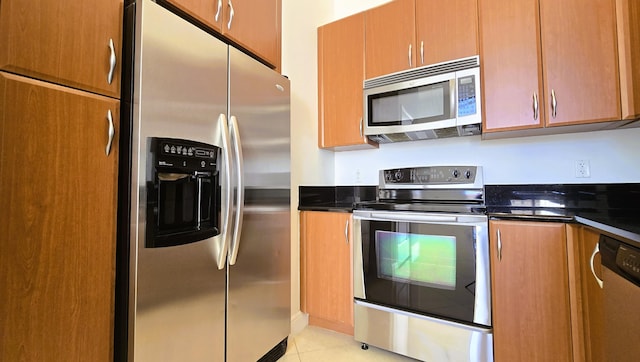 kitchen featuring stainless steel appliances, dark stone countertops, and light tile patterned floors