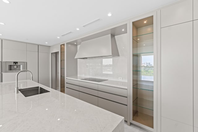 220 SE Mizner Blvd Unit 523, Boca Raton, FL 33432 - kitchen featuring wall chimney exhaust hood, modern cabinets, a sink, light stone counters, and black electric cooktop