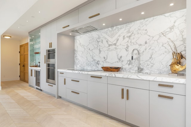 kitchen with light stone counters, sink, beverage cooler, double oven, and black electric stovetop