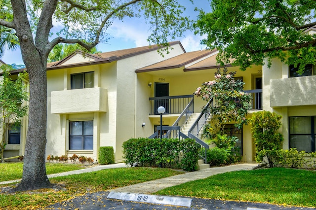 townhome / multi-family property featuring a balcony and a front lawn