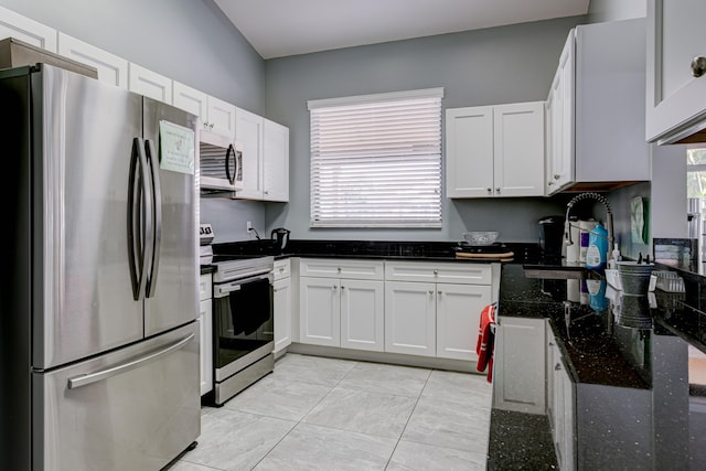 kitchen with dark stone countertops, stainless steel appliances, and white cabinets