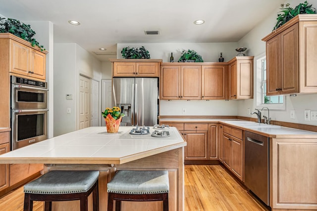 kitchen with a center island, a breakfast bar area, sink, light hardwood / wood-style flooring, and stainless steel appliances