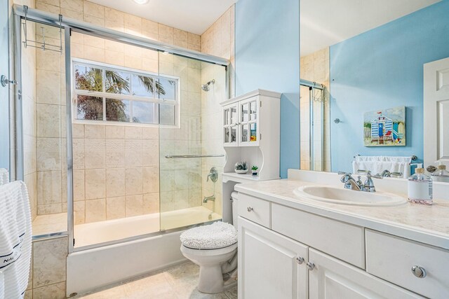 full bathroom featuring enclosed tub / shower combo, vanity, tile patterned flooring, and toilet