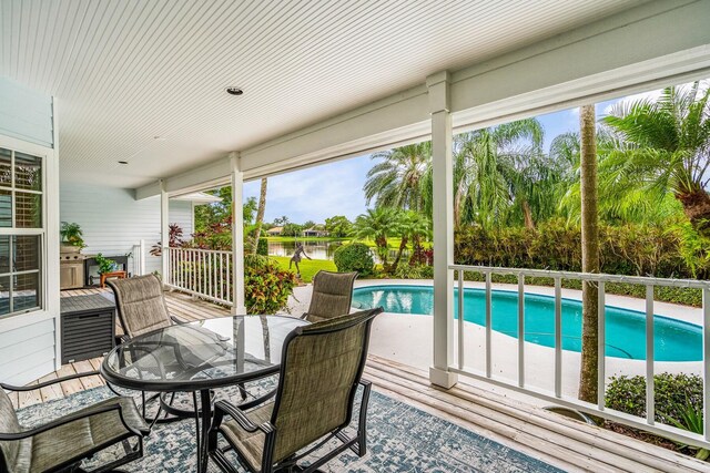 sunroom featuring a water view