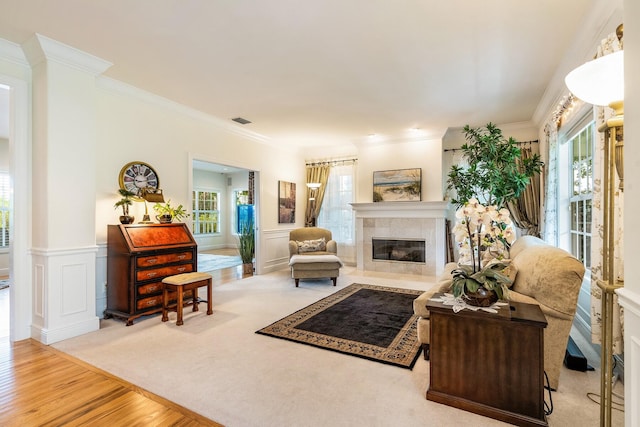 living room with light hardwood / wood-style flooring, a tiled fireplace, plenty of natural light, and ornamental molding