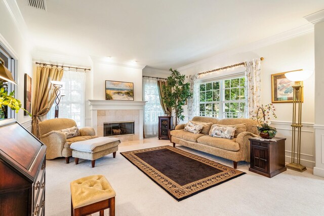 living room featuring light carpet, a tile fireplace, plenty of natural light, and crown molding