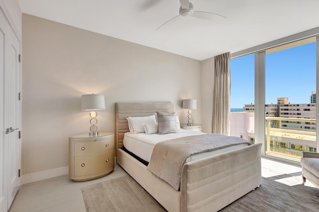 bedroom with a city view, ceiling fan, baseboards, and expansive windows