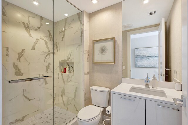 bathroom featuring toilet, tiled shower, and vanity