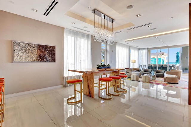 tiled dining space with a raised ceiling and a notable chandelier