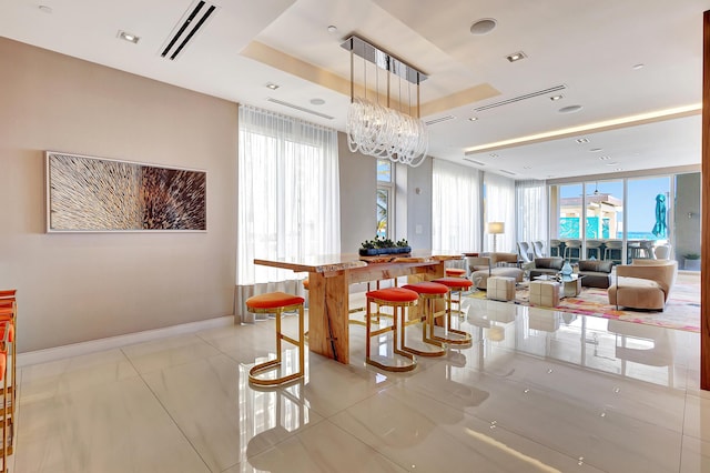 dining space with visible vents, a raised ceiling, light tile patterned flooring, baseboards, and a chandelier