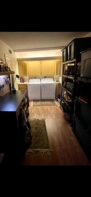 kitchen featuring independent washer and dryer, light brown cabinetry, and hardwood / wood-style floors