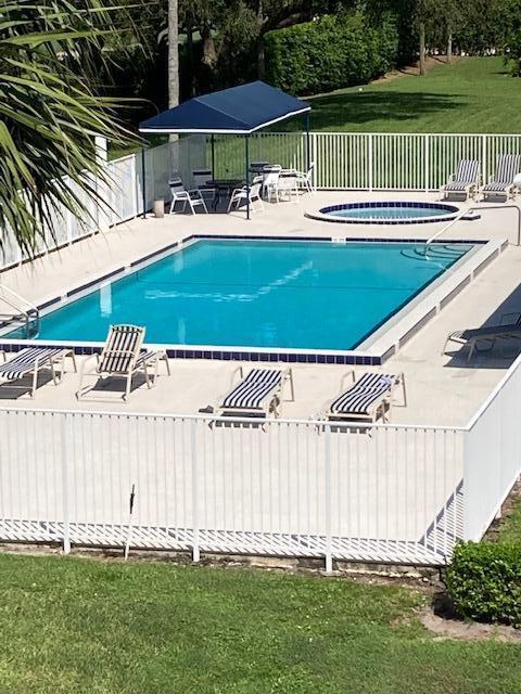 community pool featuring a lawn, fence, and a patio area