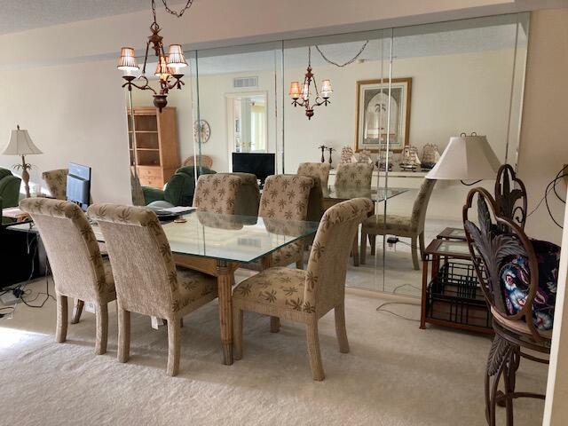 dining area featuring a chandelier, light colored carpet, and visible vents