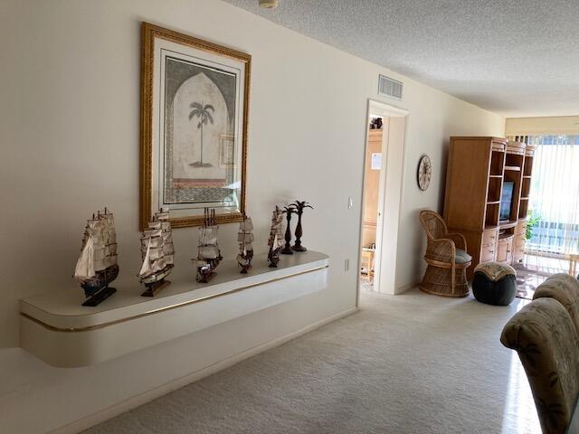 hall featuring carpet flooring, a textured ceiling, and visible vents