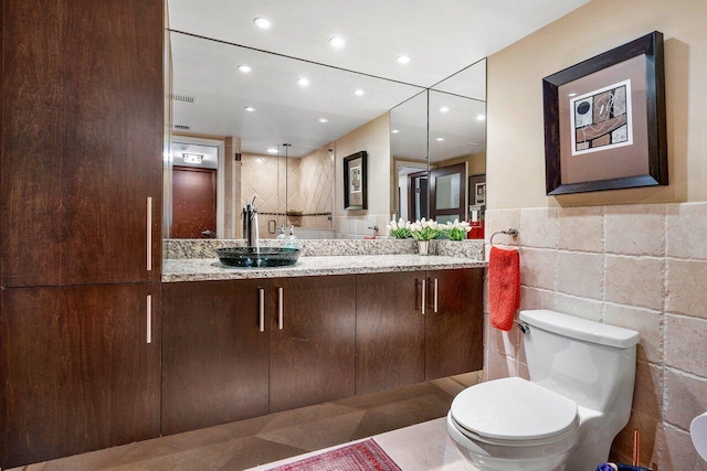 bathroom with vanity, toilet, and tile walls