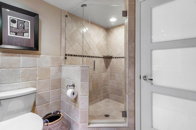 bathroom featuring tile walls, toilet, and an enclosed shower