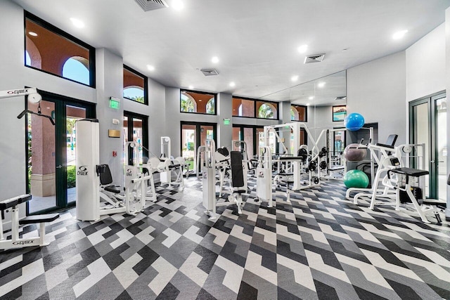 workout area with a towering ceiling, a healthy amount of sunlight, carpet floors, and french doors