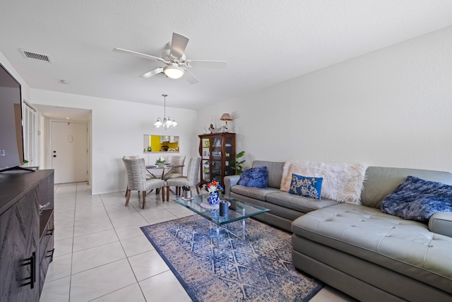 tiled living room with ceiling fan with notable chandelier and a textured ceiling